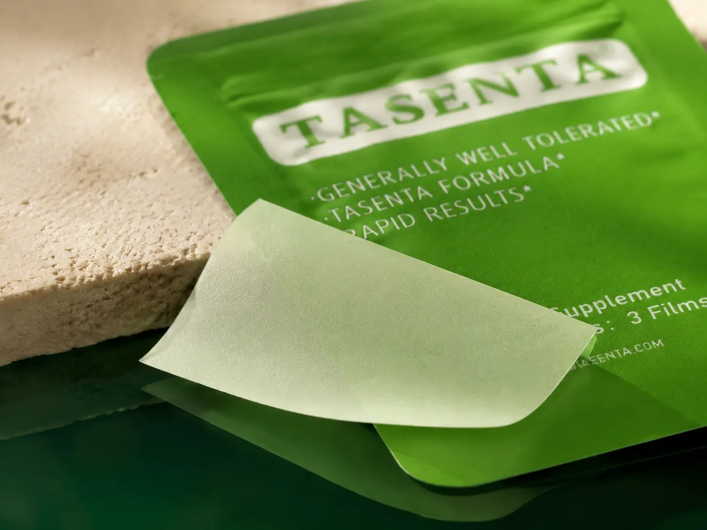 Close detail of a TASENTA oral film resting on an individual packet